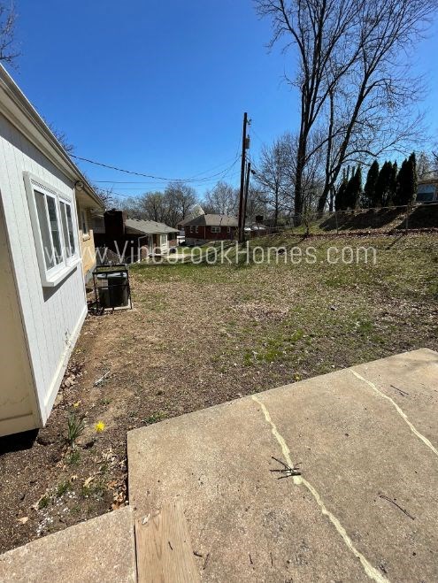 a side view of a house with a yard and a driveway