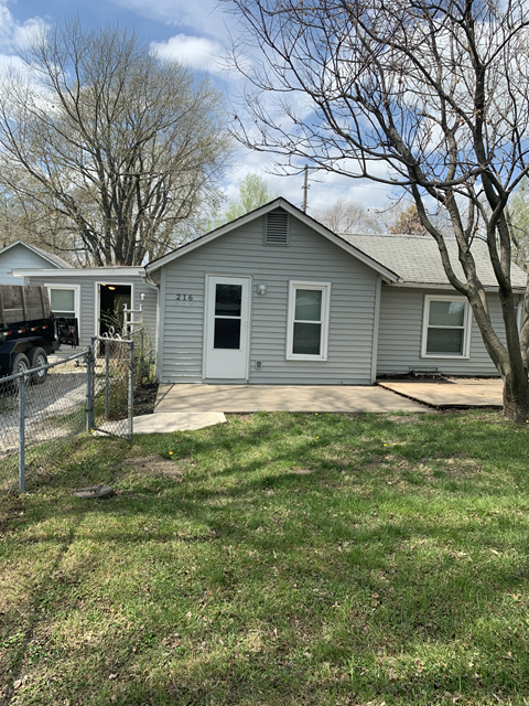a gray house with a yard and a truck in front of it