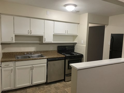 A kitchen with white cabinets and a black oven.