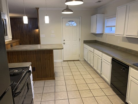 A kitchen with white cabinets and a black oven.