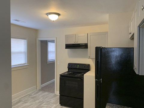 a kitchen with a stove and refrigerator and a black refrigerator freezer