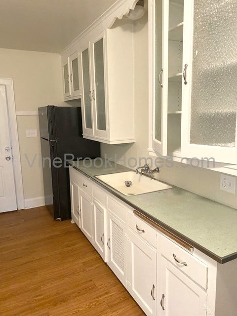 a white kitchen with white cabinets and a sink and a refrigerator
