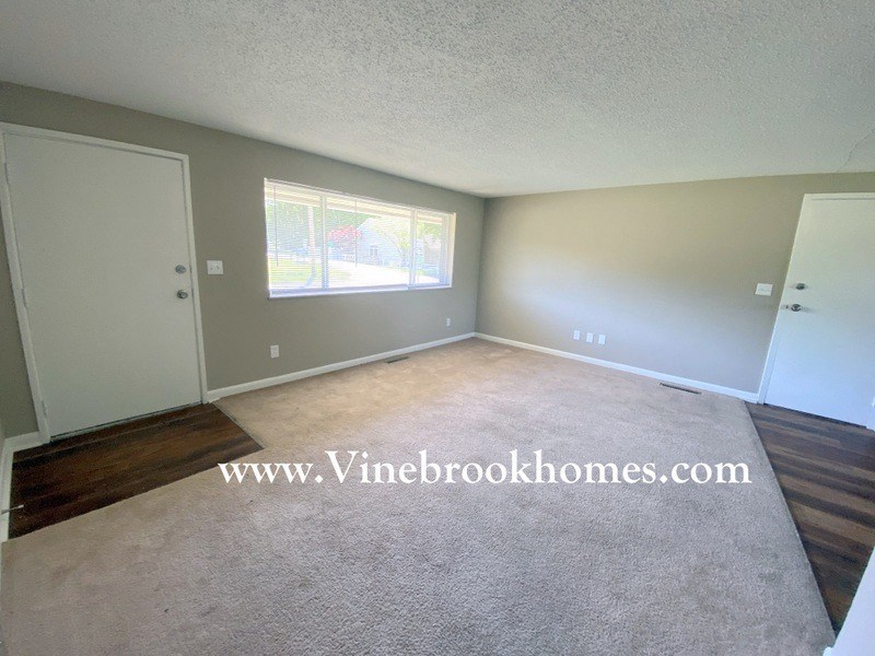 an empty living room with carpet and a window