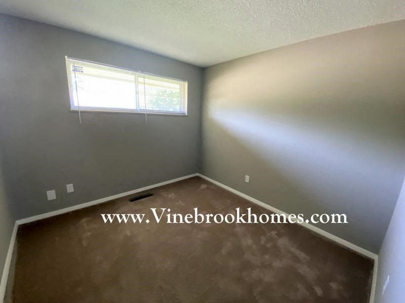 a empty bedroom with a window and a carpeted floor