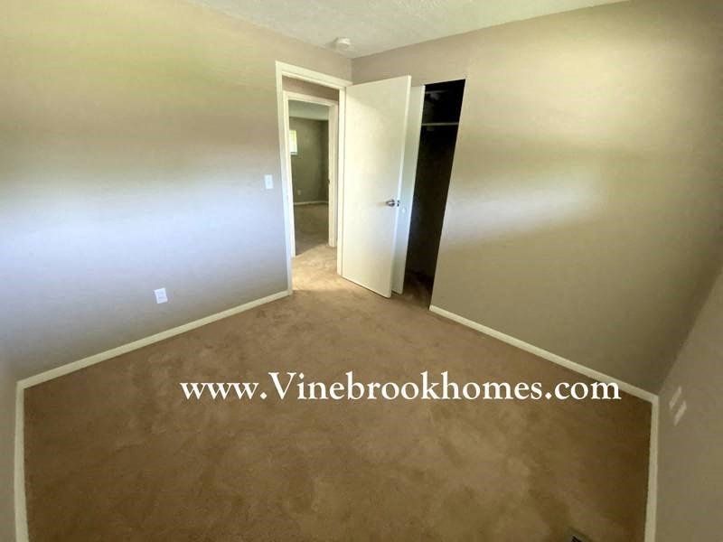 a empty room with a hallway and a door to a closet