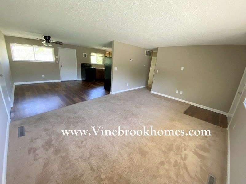 an empty living room and dining room with a hard wood floor