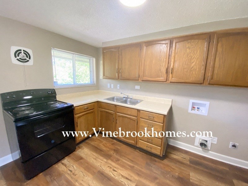 a kitchen with wood floors and a black stove and a sink