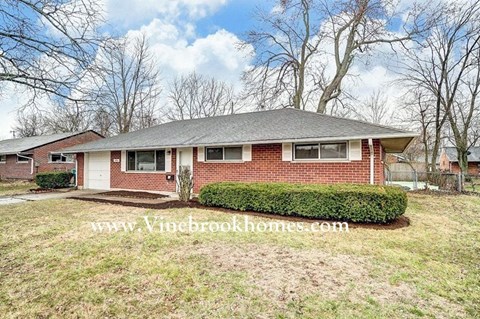 a small brick house with a yard and some trees