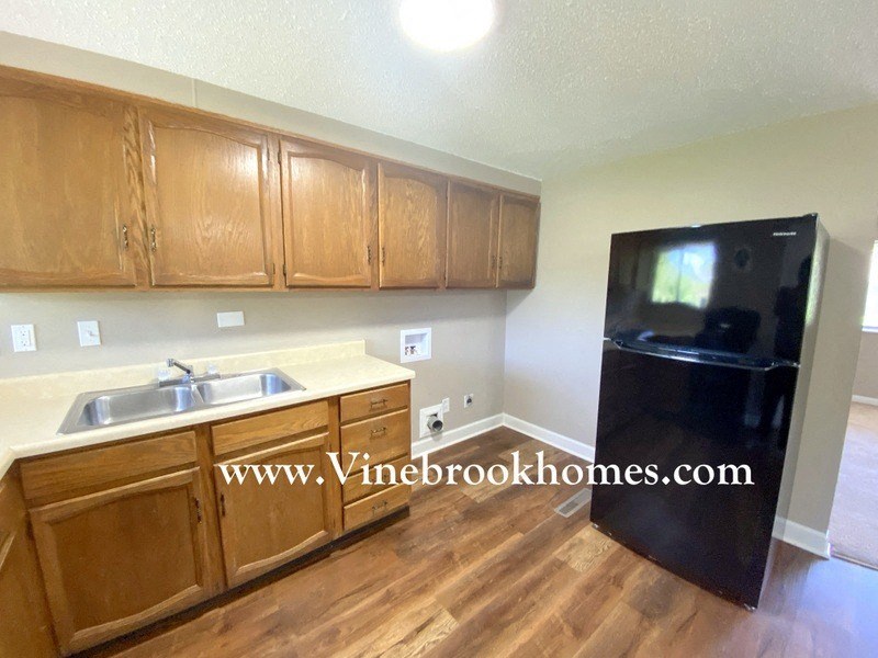 a kitchen with wooden cabinets and a black refrigerator