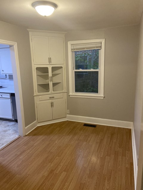 A kitchen with a wooden floor and white cabinets.