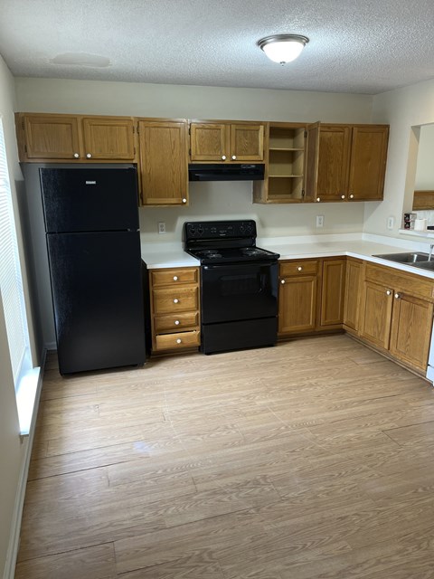 an empty kitchen with black appliances and wooden cabinets