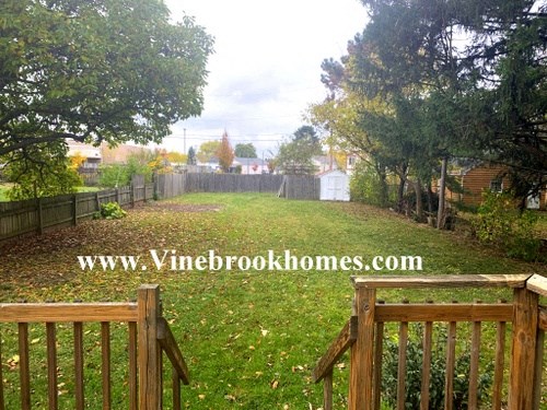a backyard with a fence and a yard with grass and trees
