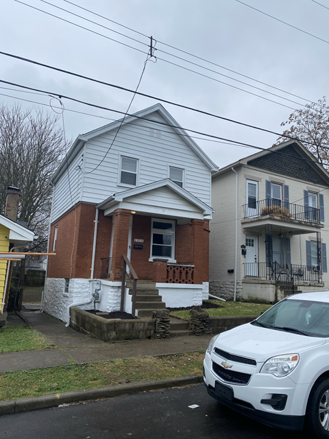 A white car is parked in front of a house.