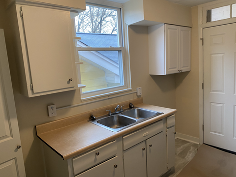 A kitchen with white cabinets and a window above the sink.