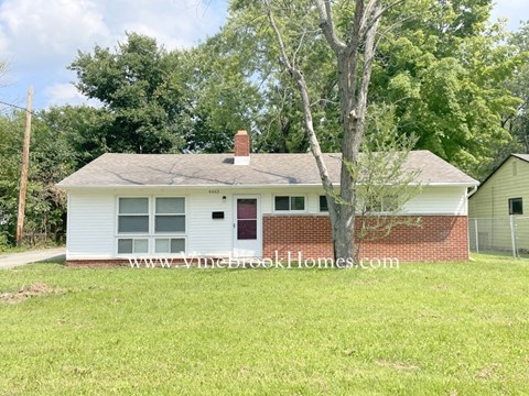 a small white house with a yard and a tree