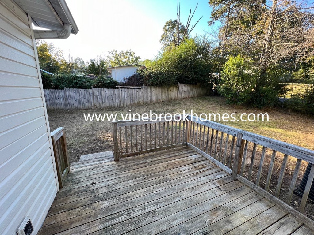 a small backyard with a wooden deck and a fence