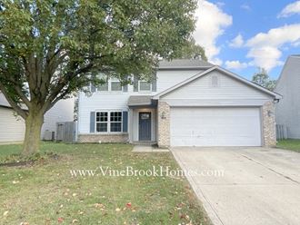 a white house with a tree in the yard and a driveway