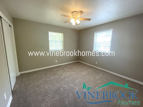 a living room with carpet and a ceiling fan