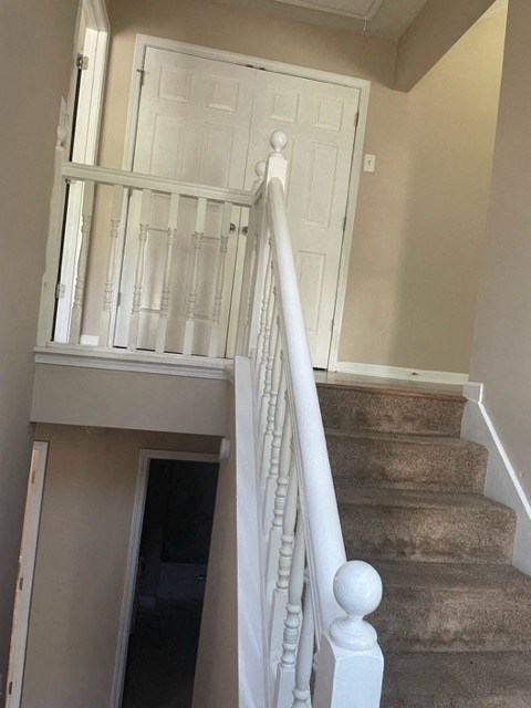 a stairway with a white railing and a white door
