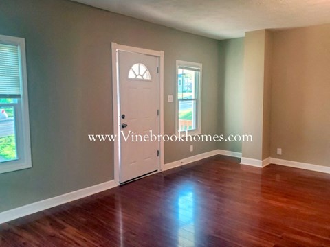 an empty living room with wooden floors and a white door