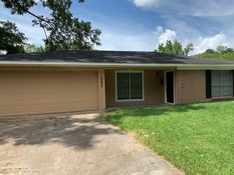 a tan house with a driveway and a garage door