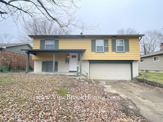 the front of a yellow house with a garage door