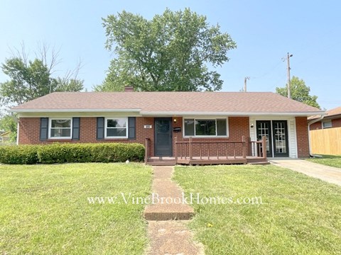 a brick house with a porch and a lawn
