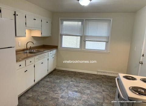 A kitchen with white cabinets and a tiled floor.