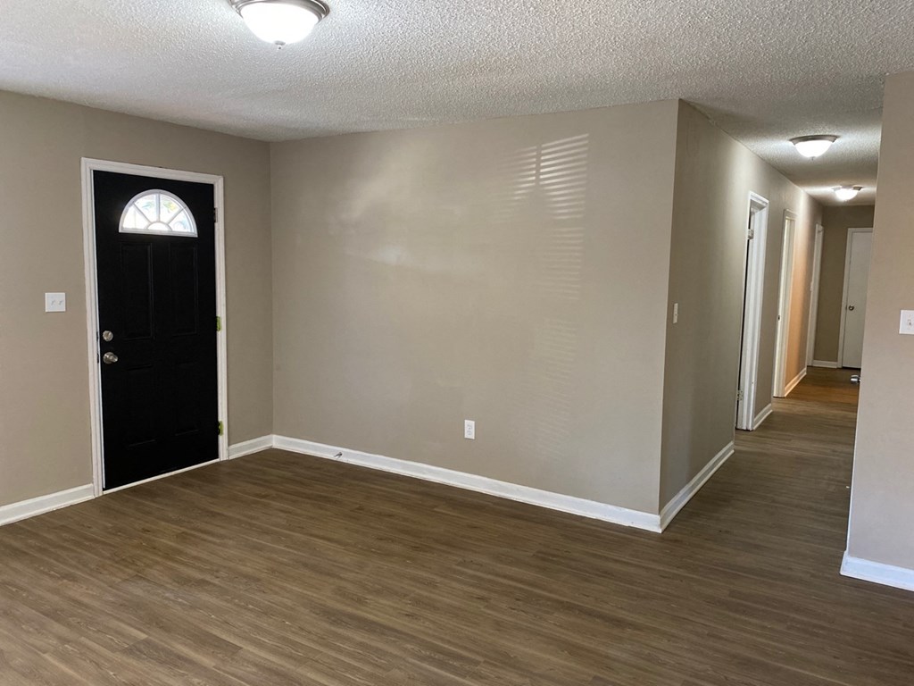 an empty living room with wooden floors and a black door