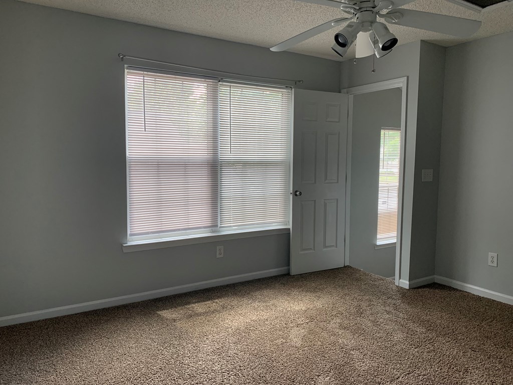 an empty room with a large window and a ceiling fan