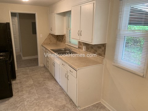 A kitchen with white cabinets and a black refrigerator.