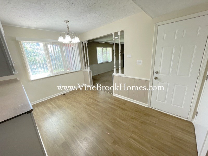 an open kitchen and living room with wood flooring and white walls