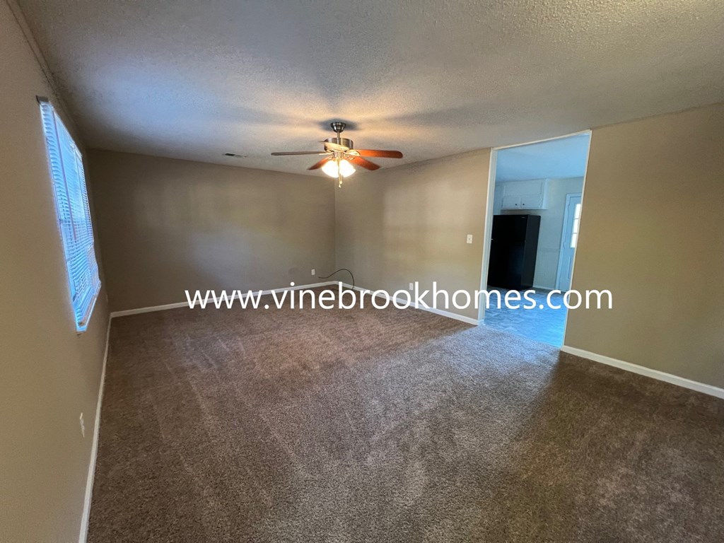 a large living room with carpet and a ceiling fan