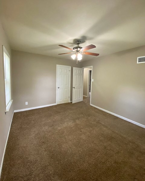 a living room with carpet and a ceiling fan