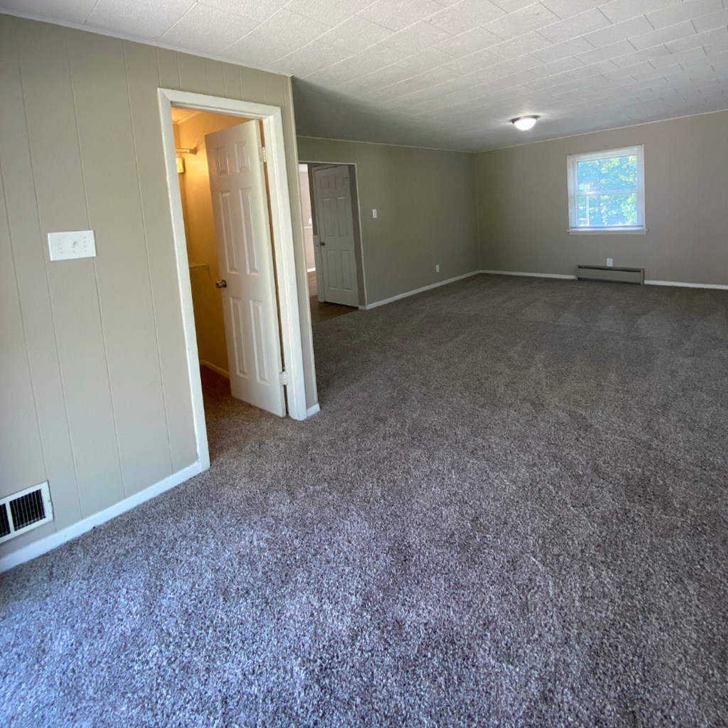 an empty living room with carpet and a door
