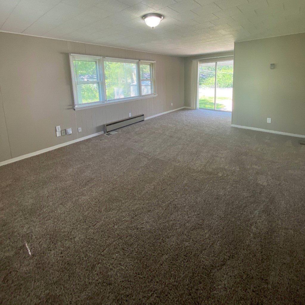 an empty living room with carpet and a window