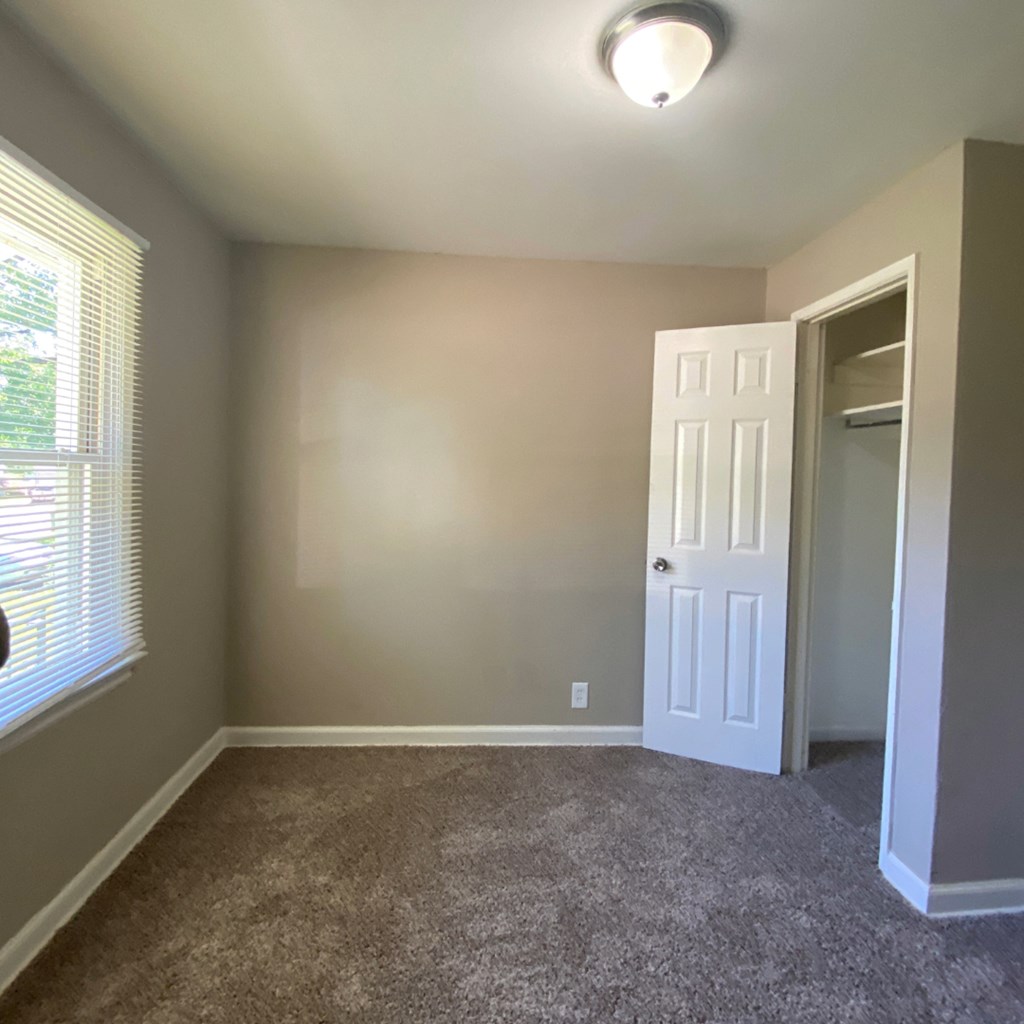a room with a carpeted floor and a door and a window