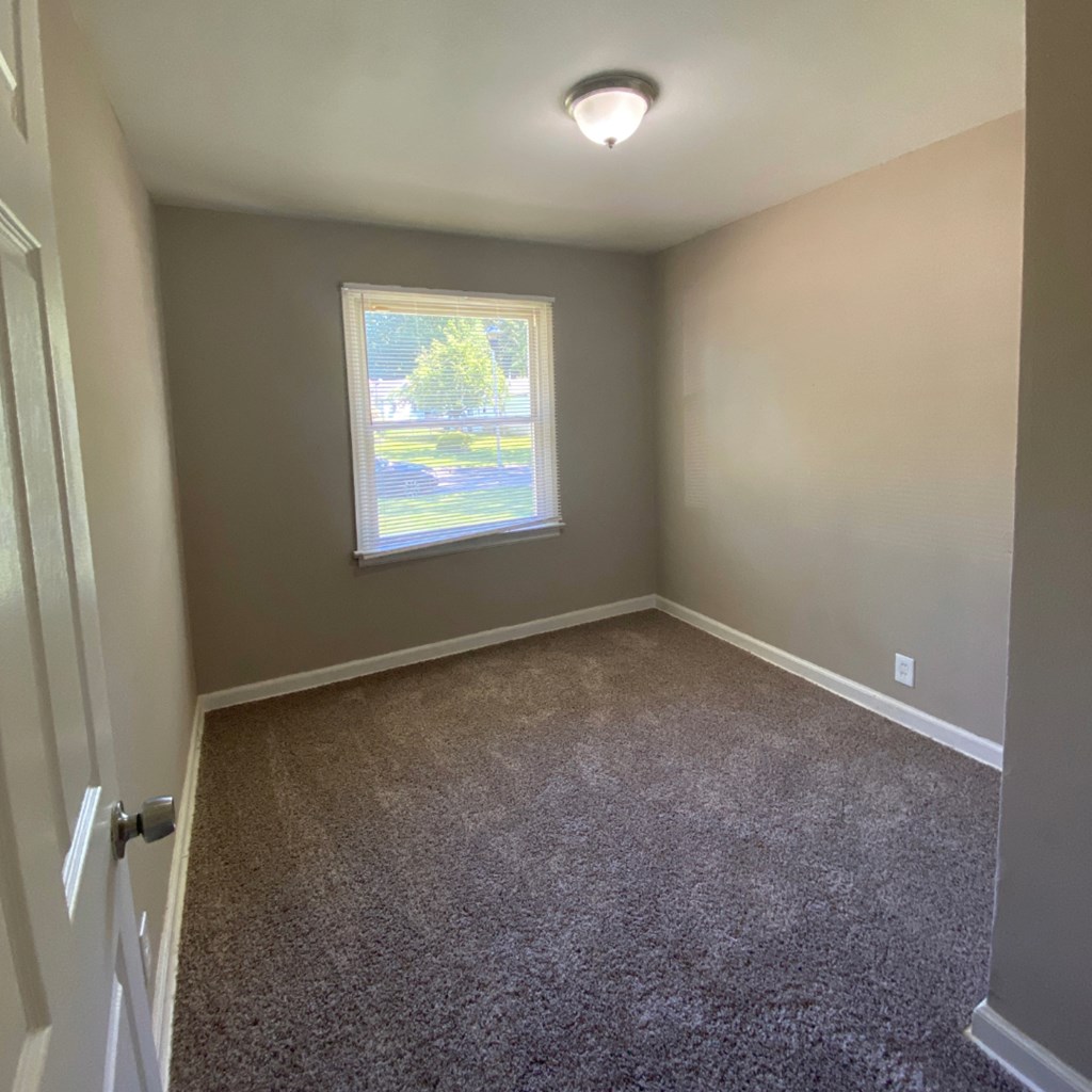 a empty room with carpet and a window