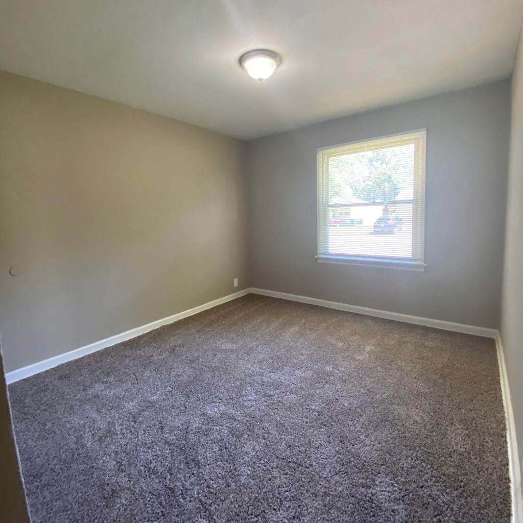 an empty room with carpet and a window