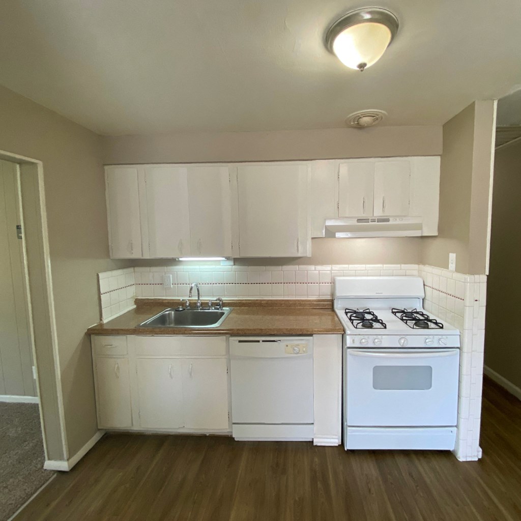 an empty kitchen with white appliances and white cabinets