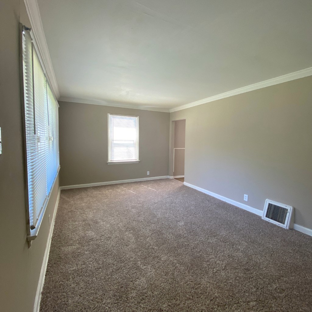 an empty living room with carpet and a window
