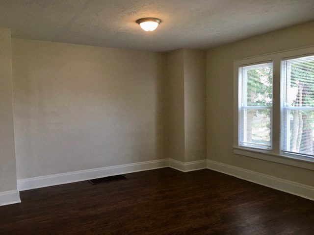 an empty room with a wood floor and two windows