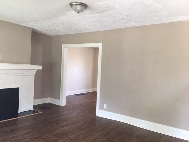 an empty living room with wood floors and a fireplace