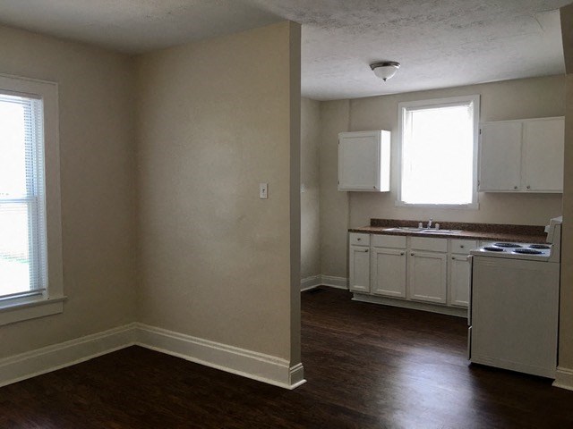 an empty kitchen with white cabinets and a sink