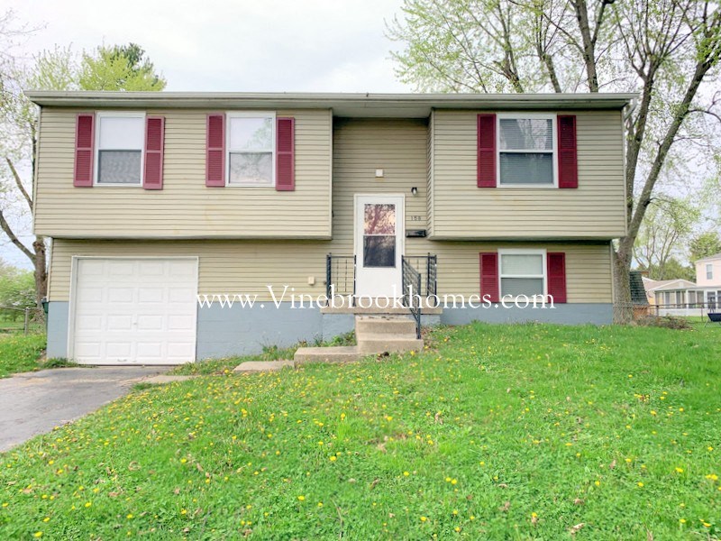a yellow house with red window shutters and a white garage door