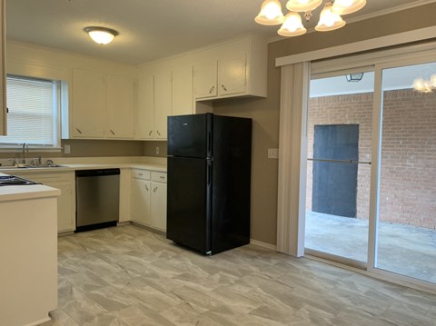 A kitchen with a black refrigerator and white cabinets.