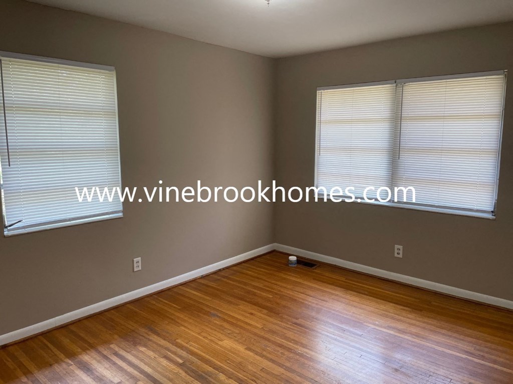 a small room with a wooden floor and two windows