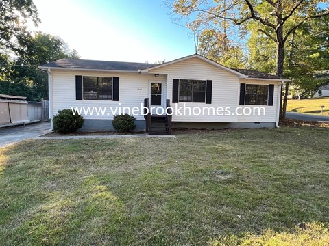 a small white house with a yard and a driveway