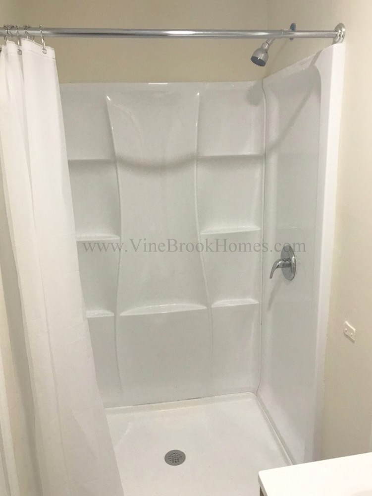 a white shower in a bathroom with a shower curtain