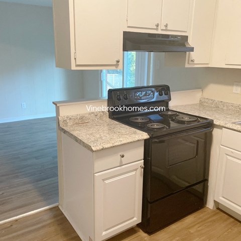 a kitchen with white cabinets and a black stove